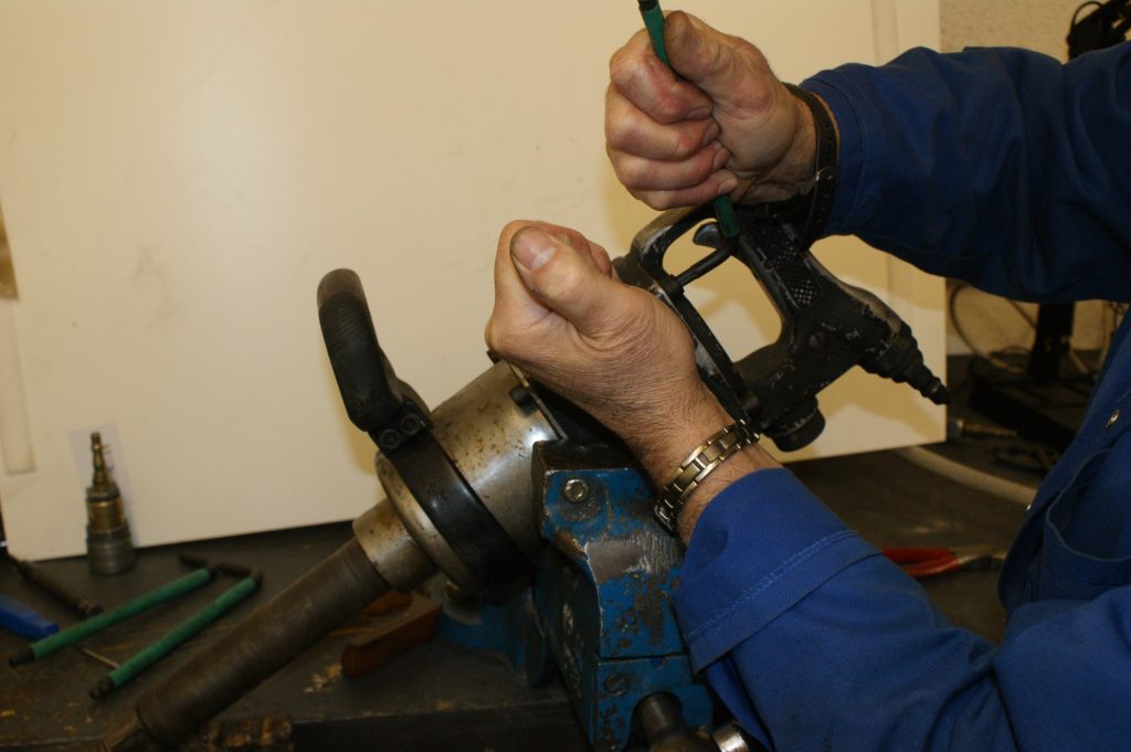 Technician repairing industrial tool with hand tools on workbench